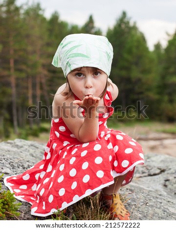 Little beautiful girl sends an air kiss on a nature.
