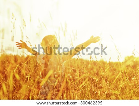 Girl lifting her hands up in the air to the sun.