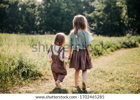 Similar – Image, Stock Photo Little girls walking barefoot on the sand and caring a picnic basket together. Summer leisure, love and friendship.