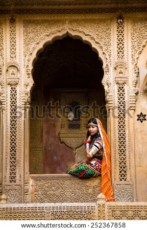Jaisalmer, India - January 7, 2015 : An indian female tourist dressed up in traditional clothing and posing in the window of the Patwon Ki haveli in Jaisalmer, India