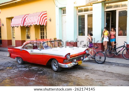 Trinidad, Cuba - 2012 December 9: A street in the colonial town of Trinidad with classic car taxi and people exiting shop, Cuba