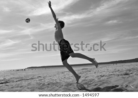 teen boy playing football on a beach, black and white photo