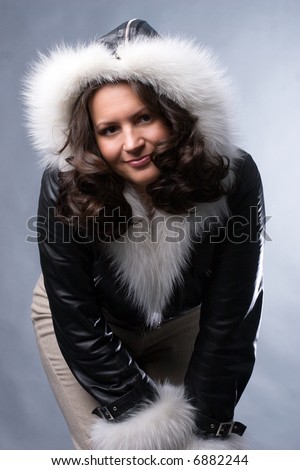 beautiful woman in black parka with white fur on blue background