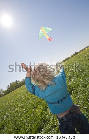 young girl flying kite on a green meadow