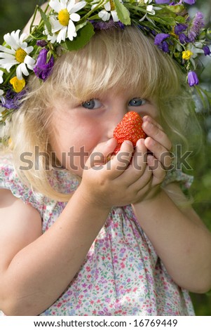 happy little girl in flowers wreath with strawberries in hands