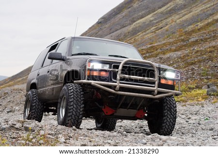 car off-road with switched on headlights on mountain background