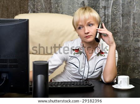 beautiful business woman sit at a table with a telephone and looks at the screen of computer