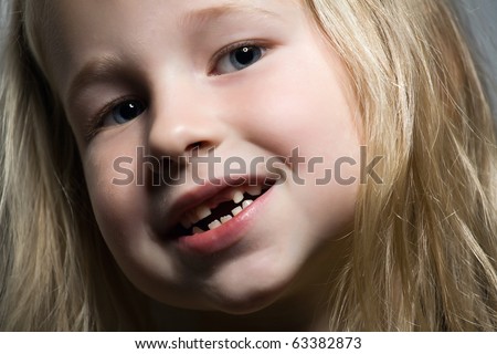 portrait of a funny little girl without one front tooth