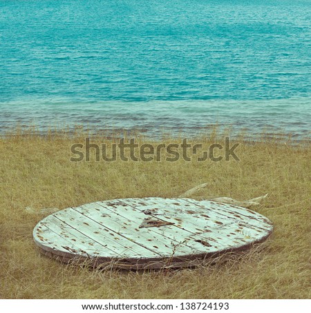wooden raft lies on a yellow grass near the blue water