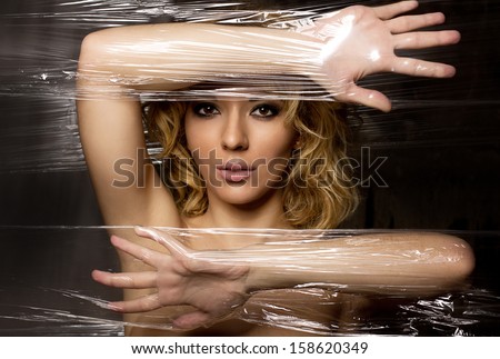 Fashion photo of beautiful woman with blond hair in plastic foil