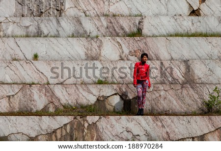 portrait of a beautiful young woman with red jacket in old marble open-cast mine