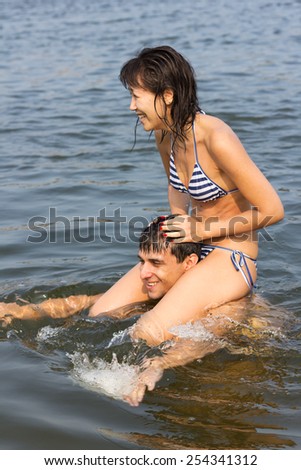 young multiethnic couple has fun in the sea, learns to swimming