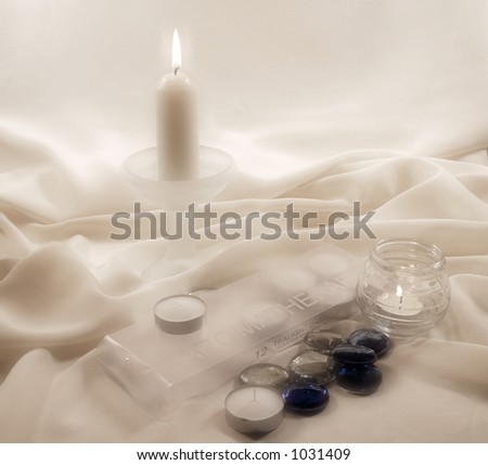 Aromatherapy candles and box with glass stones on textured soft fabric.
