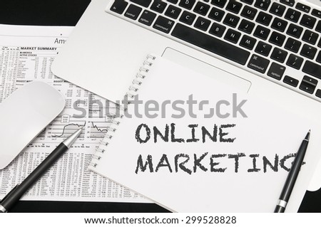 Online marketing on notepad. Background of Working Table with Laptop, Pens, Mouse. Business Concept.