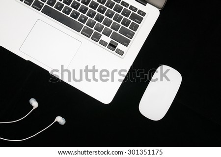 Laptop, mouse and headphones on dark background