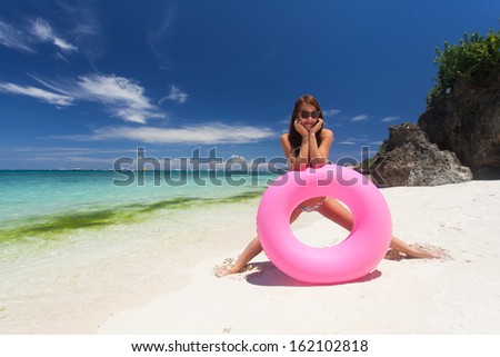 Beautiful woman posing with float tube on the beach