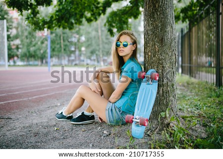 beautiful girl sitting near the skateboard in the park