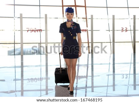 A shot of Chinese flight attendant pulling a suitcase in airport