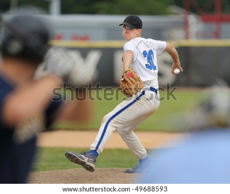 High school baseball pitcher delivering baseball to batter with umpire looking on