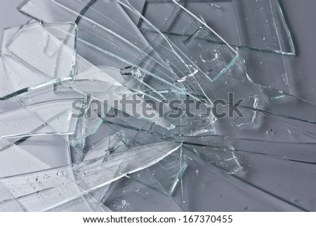 Broken glass fragments above grey. Abstract background texture