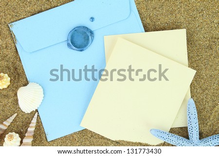 Paper card and blue envelope on the beach