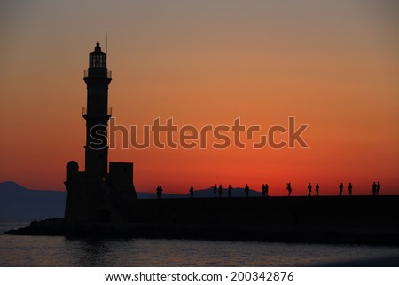 Lighthouse and people silhouettes at dusk Chania Crete