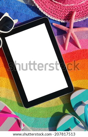 Tablet with blank screen on beach towel with accessories
