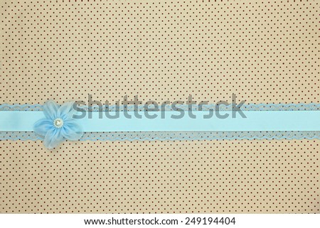 Retro beige polka dot textile background with blue ribbon and flower