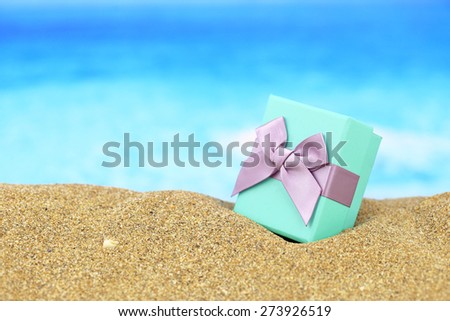 Gift box with bow on the sand