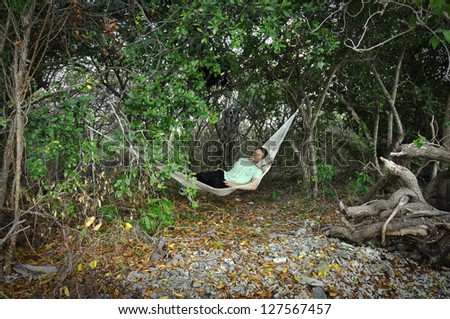 Man sleeps in Mexican hammock under trees in jungle