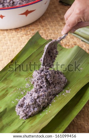 Black bean masa filling placed in banana leaf for making traditional tamales.