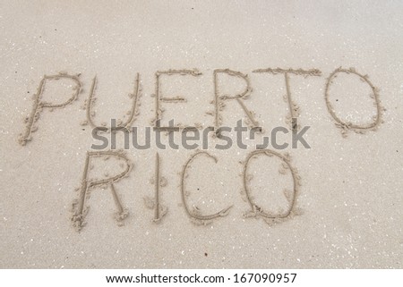 Letters PUERTO RICO carved in soft white sand of tropical beach in Puerto Rico