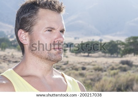 Portrait of athletic Caucasian man with serious expression of concentration staring to right of camera in outdoor environment in countryside