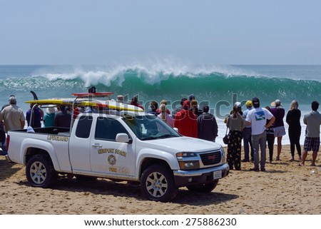 NEWPORT BEACH, USA - MAY 4, 2015: Lifeguards and spectators watch body surfers take on massive waves pounding the southern California coast at a popular surfing destination called The Wedge.