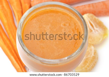 Close up of glass of carrot juice with raw carrots and oranges