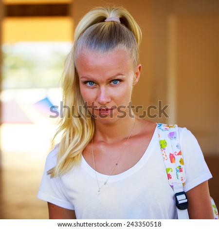 Outdoor summer portrait of pretty young blue eyed girl in a white tee shirt and with a backpack