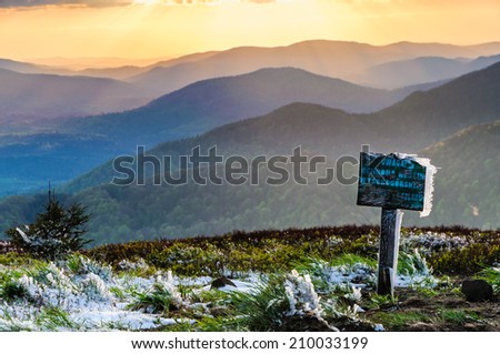 Warning signpost with last sun rays after fresh snow fall in Bieszczady national park, Poland