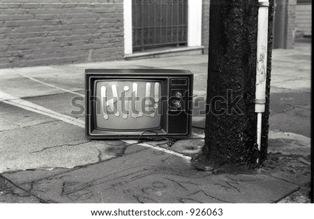 A black and white photo of a discarded TV set on which someone has painted the word kill