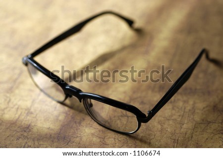 A pair of black framed eyeglasses on a wood surface in sunlight