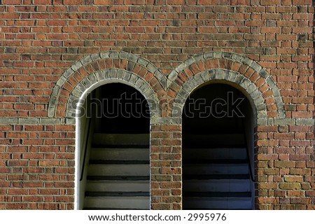 Twin arched doorways with steps leading up from the street in an old red brick European building