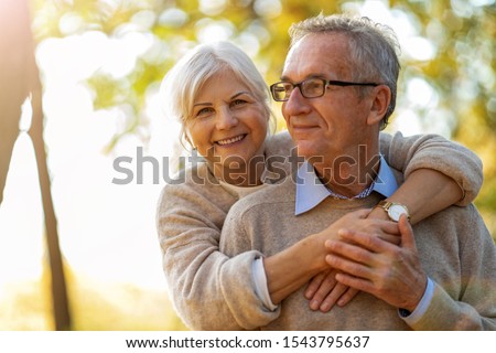 Elderly couple embracing in autumn park 
