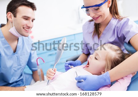 Little girl holding mirror at dentists