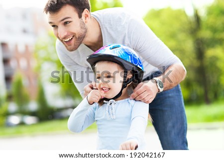 Father helping daughter with bike helmet