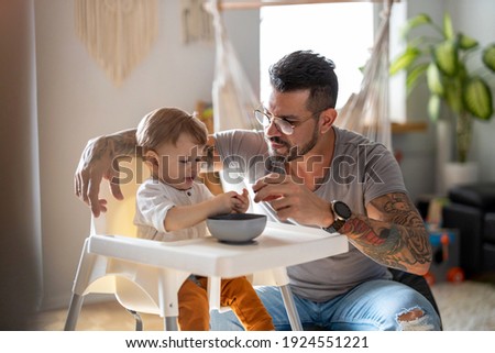 Similar – Image, Stock Photo Single dad feeding his baby who is sat in a high chair