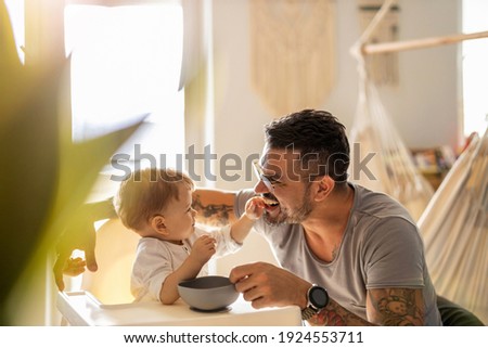 Similar – Image, Stock Photo Single dad feeding his baby who is sat in a high chair