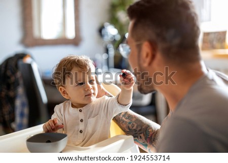 Similar – Image, Stock Photo Single dad feeding his baby who is sat in a high chair