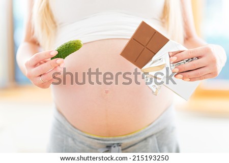 Pregnant woman holding pickle and chocolate