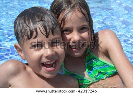Smiling children in the swimming pool of water park in sunny summer day