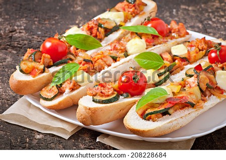Big sandwich with roasted vegetables (zucchini, paprika , tomatoes) with cheese and basil on old wooden background