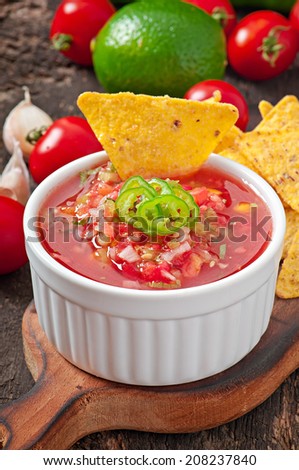 Mexican nacho chips and salsa dip in  bowl on  wooden background